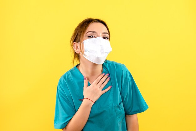 Front view of female veterinarian wearing mask on yellow wall