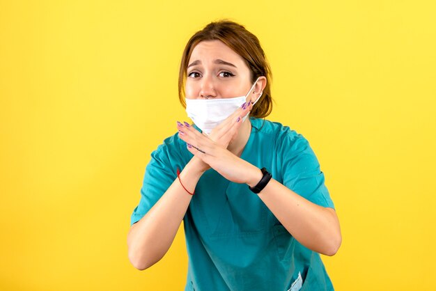 Front view of female veterinarian wearing mask on yellow wall