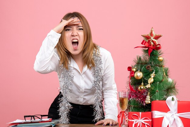 Front view of female worker around christmas presents on pink