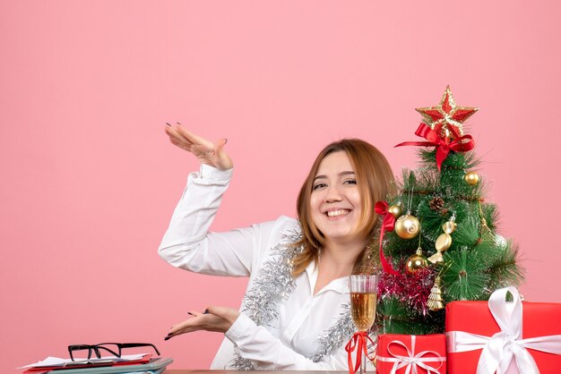 Front view of female worker around christmas presents on pink