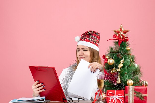 Front view of female worker checking documents on pink