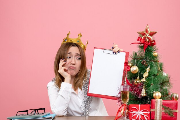 Front view of female worker in crown holding file note on pink