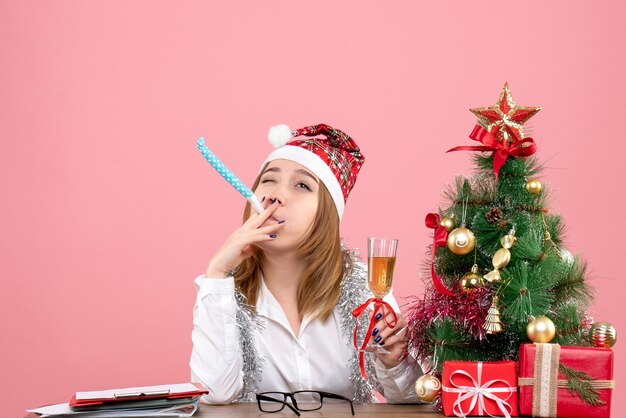 Front view of female worker holding glass of champagne on pink