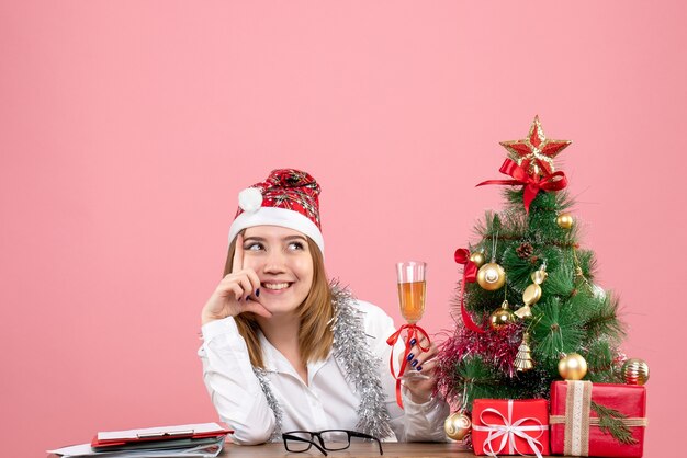 Front view of female worker holding glass of champagne on pink