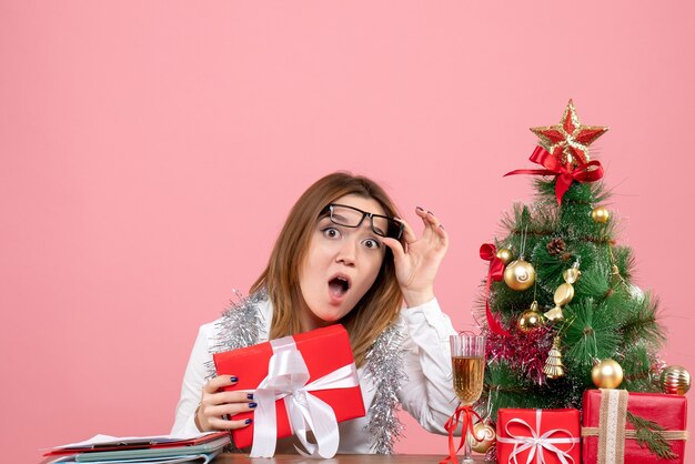 Front view of female worker holding present on pink