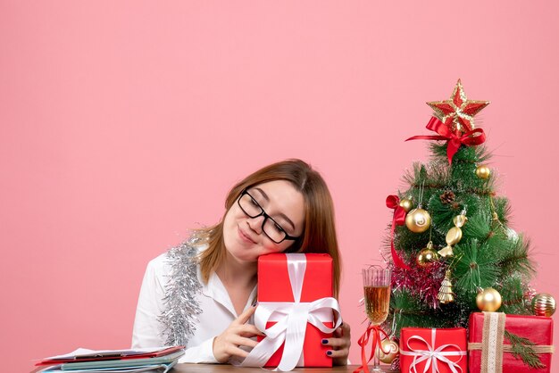 Front view of female worker holding present on pink.