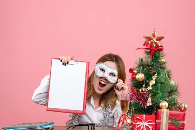 Front view of female worker in party mask with file note on pink