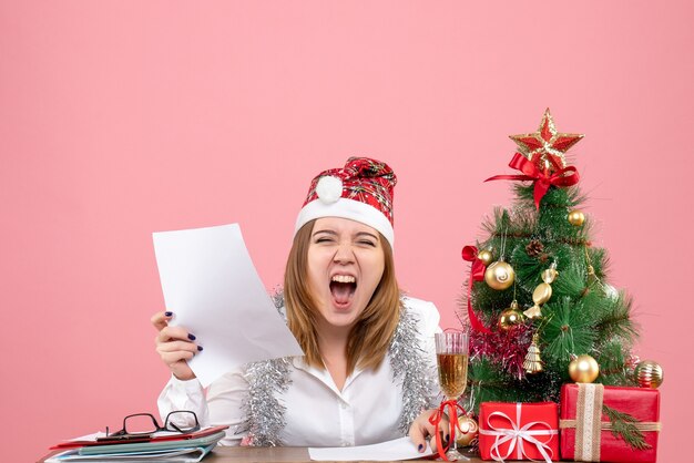 Front view of female worker reading documents on pink