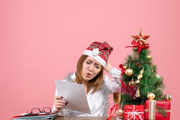 Front view of female worker reading documents on pink