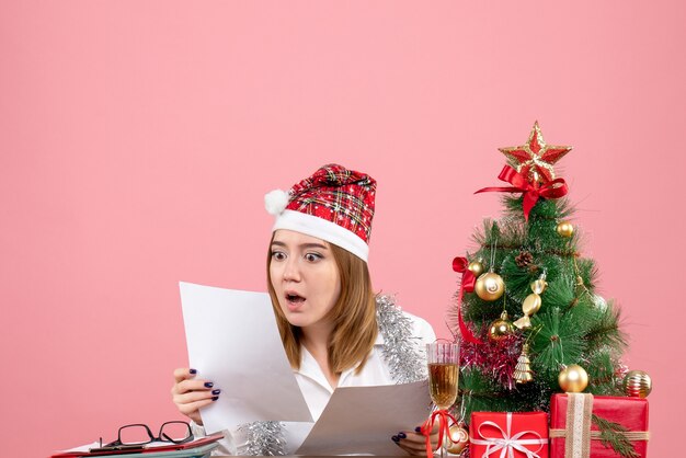 Front view of female worker reading documents on pink