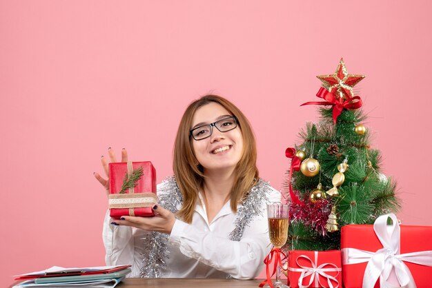 핑크에 크리스마스 선물과 나무 주위에 앉아 여성 노동자의 전면보기
