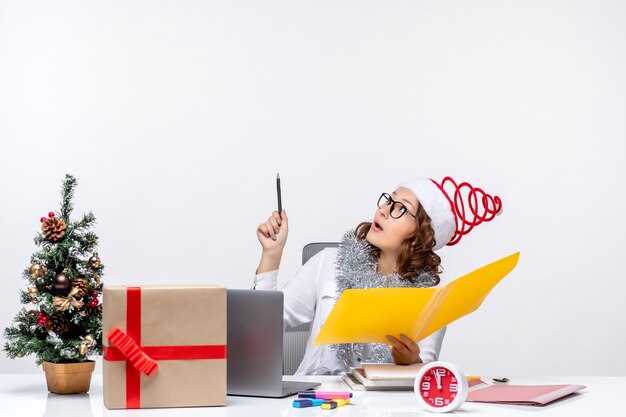 Front view female worker sitting before her place and working with documents business office work christmas job