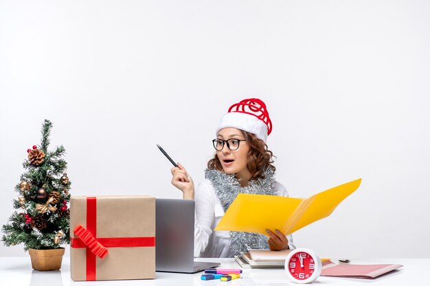 Front view female worker sitting before her place and working with documents work business christmas job