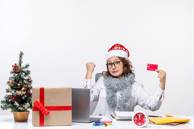 銀行カードの仕事の仕事のクリスマスオフィスの女性を保持している彼女の職場の前に座っている正面図の女性労働者