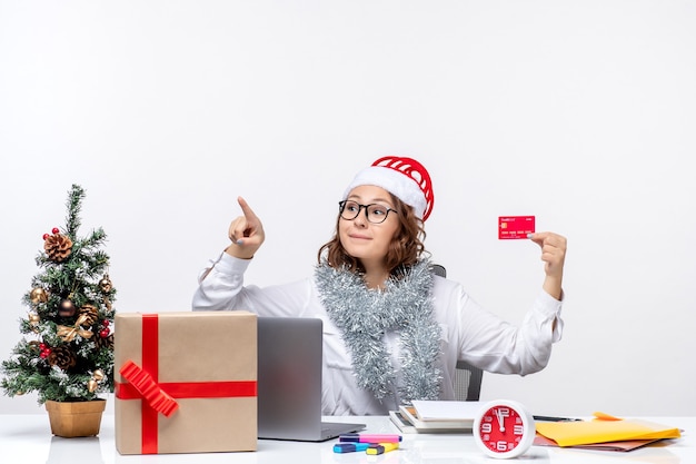 Front view female worker sitting before her working place holding bank card woman job work christmas office