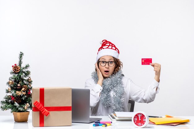 Front view female worker sitting before her working place holding bank card