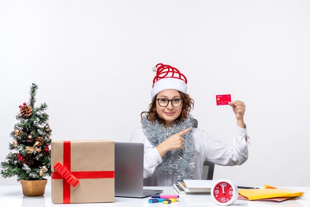 Front view female worker sitting before her working place holding bank card