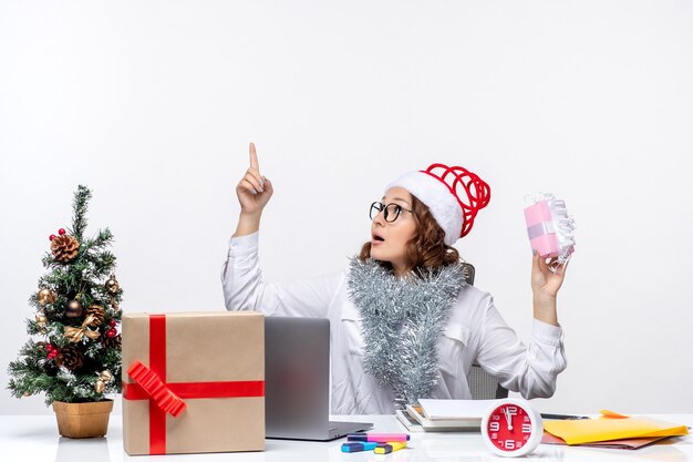 少し現在の仕事クリスマスオフィスの仕事ビジネスを保持している彼女の職場の前に座っている正面図の女性労働者