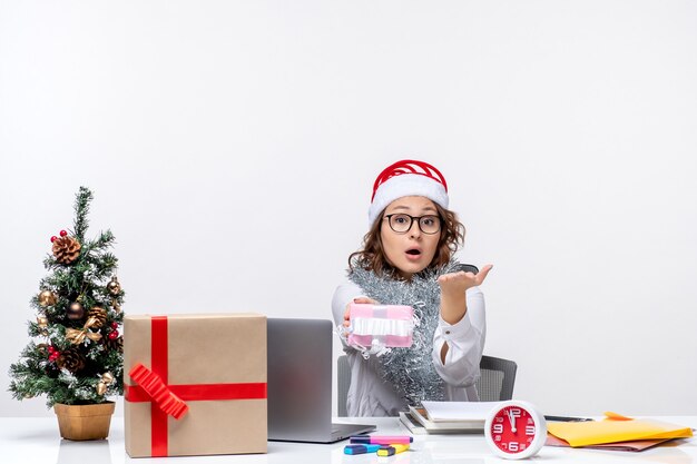 Front view female worker sitting before her working place holding little present