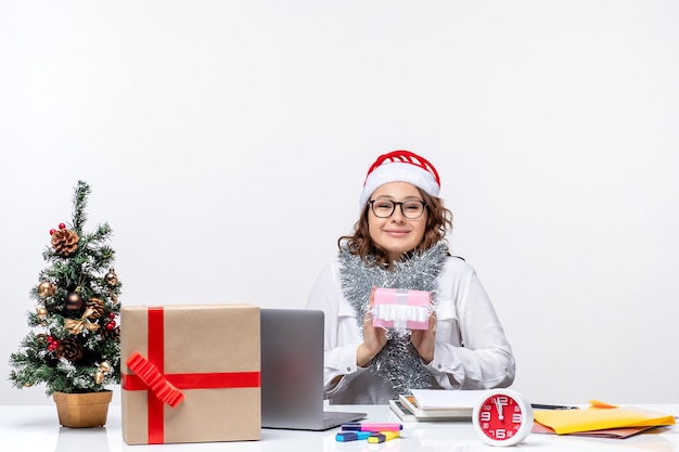 Front view female worker sitting before her working place holding little present