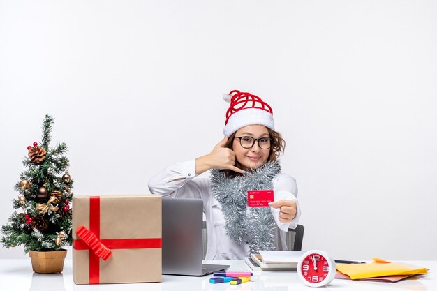 Front view female worker sitting before her working place holding red bank card