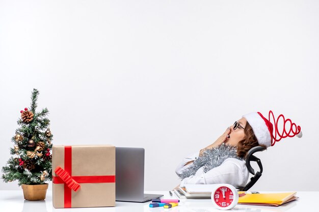 Front view female worker sitting before her working place and trying to sleep office work business christmas job