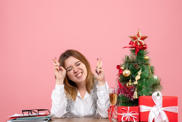 Front view of female worker sitting behind her table with presents hoping on pink