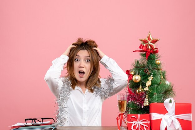 Front view of female worker sitting behind her table with presents on pink