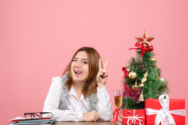 Front view of female worker sitting behind her table with presents on pink