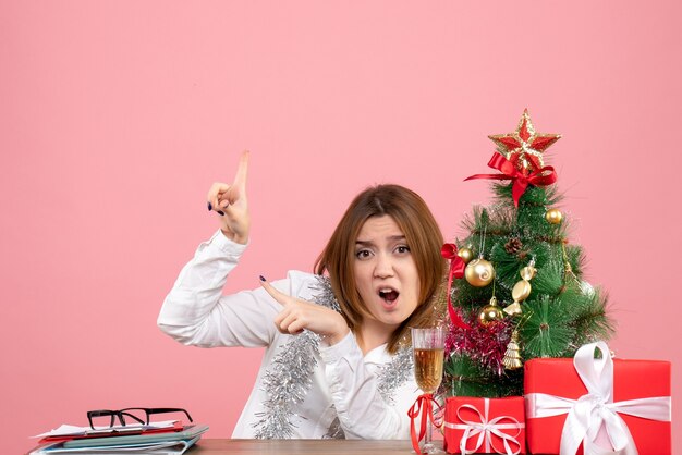 Front view of female worker sitting behind her table with presents on pink