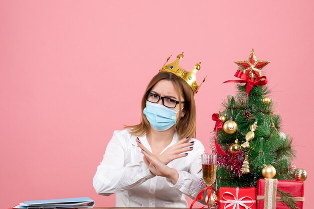 Front view of female worker sitting in sterile mask on pink