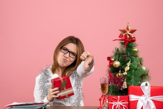 Front view of female worker sitting with christmas presents on pink