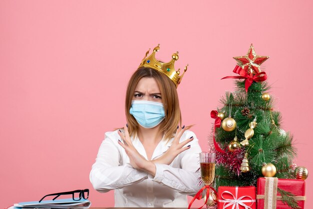 Front view of female worker in sterile mask with crown on pink