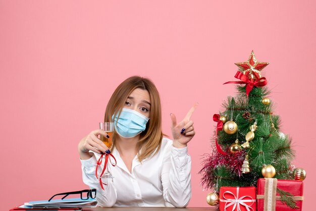 Front view of female worker in sterile mask with presents on pink