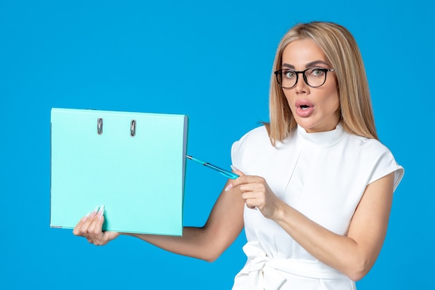 Free photo front view of female worker in white dress holding blue folder on blue wall