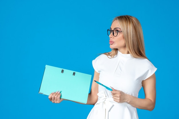 Free photo front view of female worker in white dress holding blue folder on blue wall