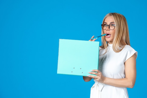 Free photo front view of female worker in white dress holding folder on blue wall