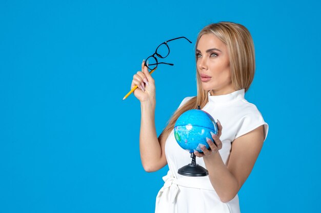 Free photo front view of female worker in white dress holding little earth globe on blue wall