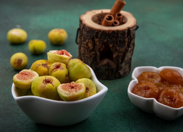 Front view figs and jam in saucers with cinnamon on a green background