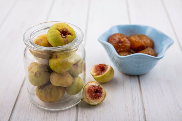 Front view figs in a jar with fig jam in a bowl on a white background