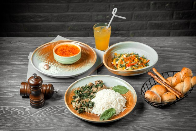 Вид спереди первое второе и основное блюдо суп из чечевицы овощной салат и рис с мясом и соком на столе