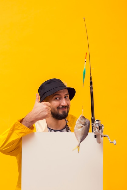 Front view of fisherman holding fishing rod and giving thumbs up