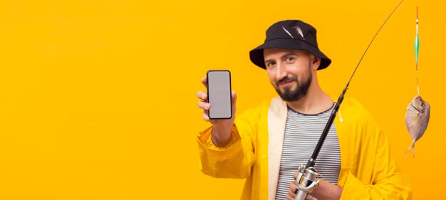 Front view of fisherman holding fishing rod and smartphone