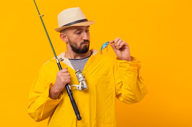 Free photo front view of fisherman looking at bait while holding fishing rod