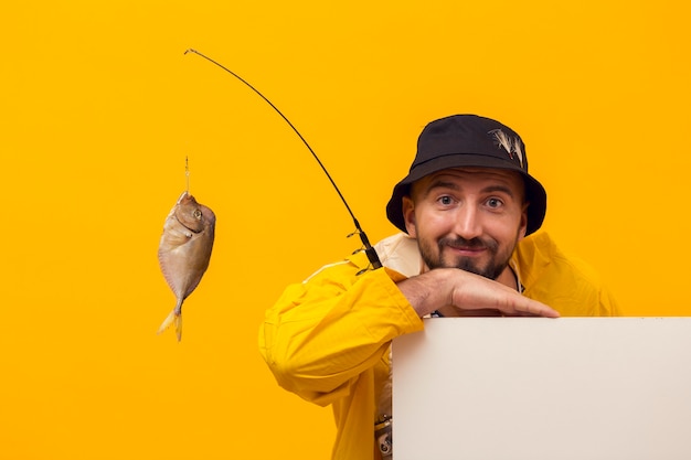 Front view of fisherman posing while holding fishing rod with catch