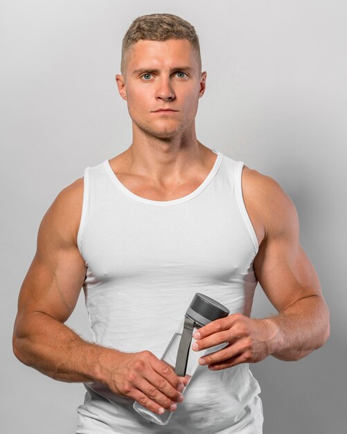 Front view of fit man holding water bottle
