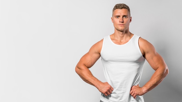 Front view of fit man posing while wearing tank top with copy space