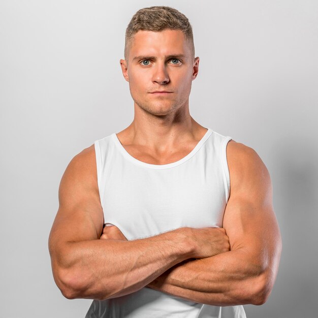 Front view of fit man posing while wearing tank top with crossed arms