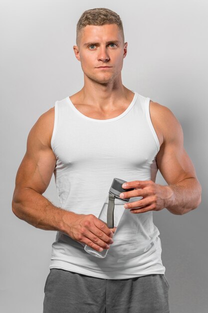 Front view of fit man in tank top holding water bottle