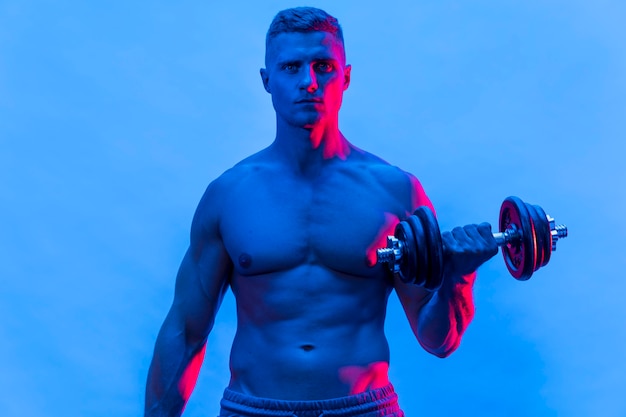 Front view of fit shirtless man exercising with weights